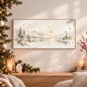Könnte beinhalten: Ein rechteckiger Wandkunstdruck mit einer Aquarell-Winterlandschaft, die schneebedeckte Berge, einen ruhigen See und immergrüne Bäume zeigt. Das Bild enthält goldene Sternakzente, Tannenzweige mit roten Beeren und eine sanft leuchtende Sonne.