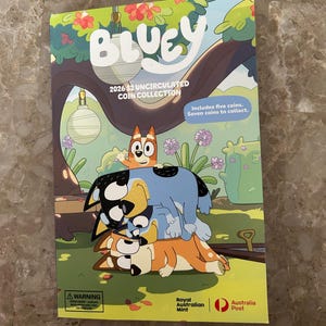 Könnte beinhalten: Eine farbenfrohe Bluey-Münzsammlung mit den Zeichentrickfiguren Bluey, Bingo und anderen Charakteren. Auf dem Cover steht "BLUEY 2026 $2 UNCIRCULATED COIN COLLECTION" und enthält den Text "Includes five coins. Seven coins to collect."