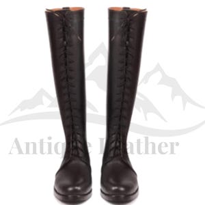 Puede incluir: Un par de botas de montar de cuero negro. Las botas son altas, con cordones en la parte delantera y un acabado liso. Botas de equitación para montar a caballo.