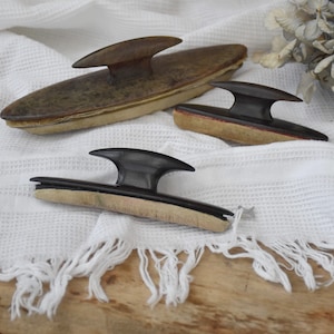 Peut inclure: Trois applicateurs de cirage à chaussures vintage avec des poignées noires et des bases en bois. Les applicateurs sont sur un tissu blanc avec une frange.