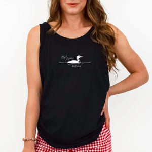 Könnte beinhalten: Schwarzes Tanktop mit einer weißen Grafik eines Eistauchers, der auf dem Wasser schwimmt, mit dem Text "Stupid Canadian Wolf bird". Das Oberteil ist ärmellos und hat einen runden Ausschnitt. Das Model trägt einen rot-weiß karierten Rock.