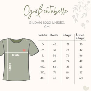 Pu&ograve; includere: Una tabella delle taglie per una t-shirt unisex Gildan 5000 con l'illustrazione di una t-shirt verde oliva chiaro con un piccolo cuore rosso. La tabella elenca le taglie dalla S alla 4XL con misure di larghezza, lunghezza e manica in centimetri.