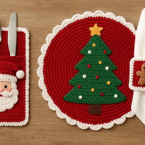 Może przedstawiać: Świąteczna dekoracja stołu bożonarodzeniowego z czerwoną szydełkową kieszenią na sztućce Świętego Mikołaja z widelcem i nożem, czerwoną podkładką z zieloną choinką i serwetnikiem z piernikowym ludzikiem. Zestaw jest obszyty na biało.