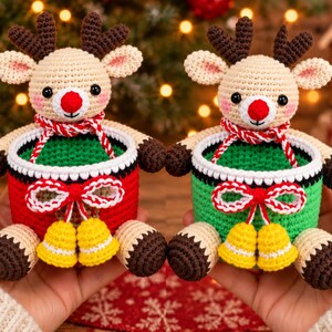 May include: Two crocheted reindeer baskets featuring beige heads with dark brown antlers, red noses, and pink cheeks. Each basket has a white rim, a red or green body, and a decorative red and white cord bow with two small yellow bells attached.