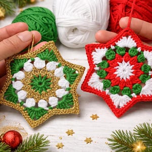 May include: Two handmade star-shaped Christmas ornaments. One is green, white, and gold, the other is red, white, and green. Yarn balls in green, white, and red are in the background, along with Christmas decorations.
