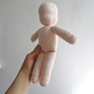 May include: A pink fabric doll with a simple design. The doll has a head, arms, and legs, and is made of a soft, plush fabric.