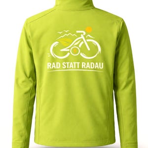 Könnte beinhalten: Hellgrüne Jacke mit Reißverschluss und hohem Kragen. Die Jacke hat eine weiße und gelbe Grafik eines Fahrrads, einer Sonne und Blättern mit dem weißen Text "RAD STATT RADAU". Die Jacke ist aus einem glatten, leichten Material gefertigt.