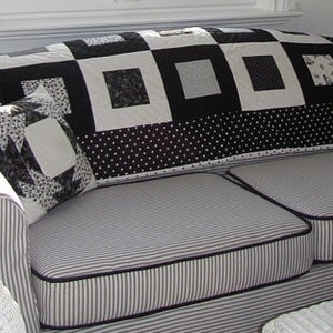 Könnte beinhalten: Ein schwarz-weiß gestreiftes Sofa mit einem schwarz-weiß gemusterten Kissen und einer schwarz-weiß gestreiften Decke.