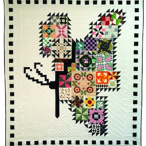 May include: A white quilt with a black and white checkered border. The center of the quilt features a large butterfly design made of colorful patchwork fabric squares.