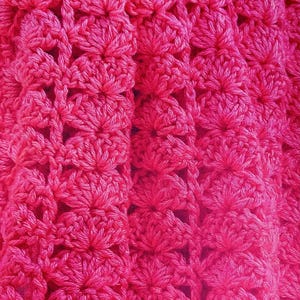 Puede incluir: Primer plano de una tela de crochet rosa con un patrón de flores repetido.