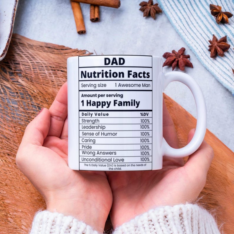 May include: White ceramic mug with a black and white graphic that reads "DAD Nutrition Facts" with a list of qualities and a percentage daily value for each. The qualities listed are Strength, Leadership, Sense of Humor, Caring, Pride, Wrong Answers, and Unconditional Love. Each quality has a percentage daily value of 100%.
