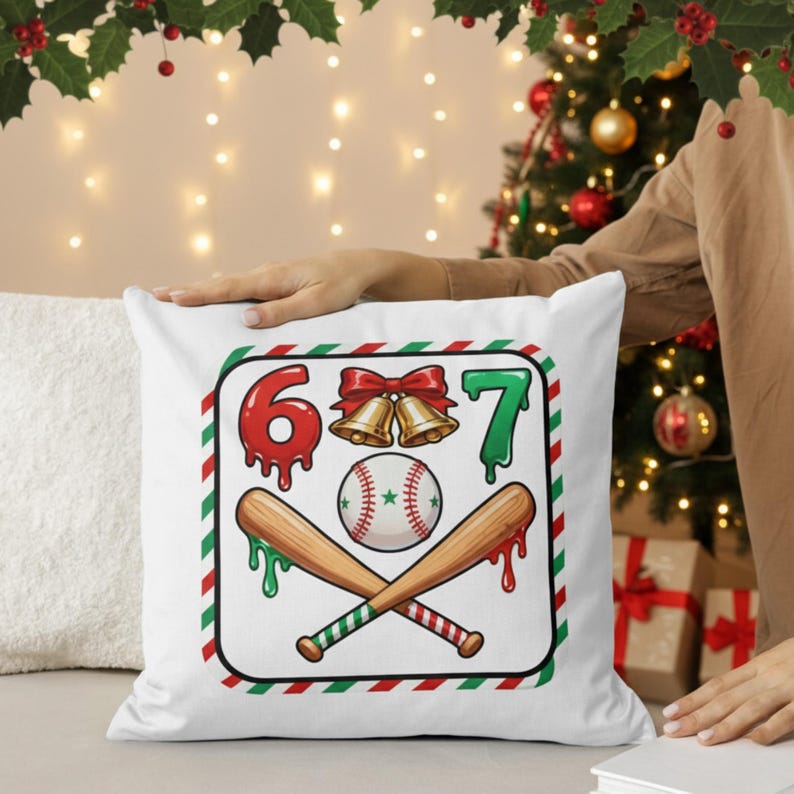 May include: White square pillow with a baseball-themed Christmas design. The design includes the numbers 6 and 7, a baseball, crossed bats, and bells. The numbers and dripping accents are red and green.