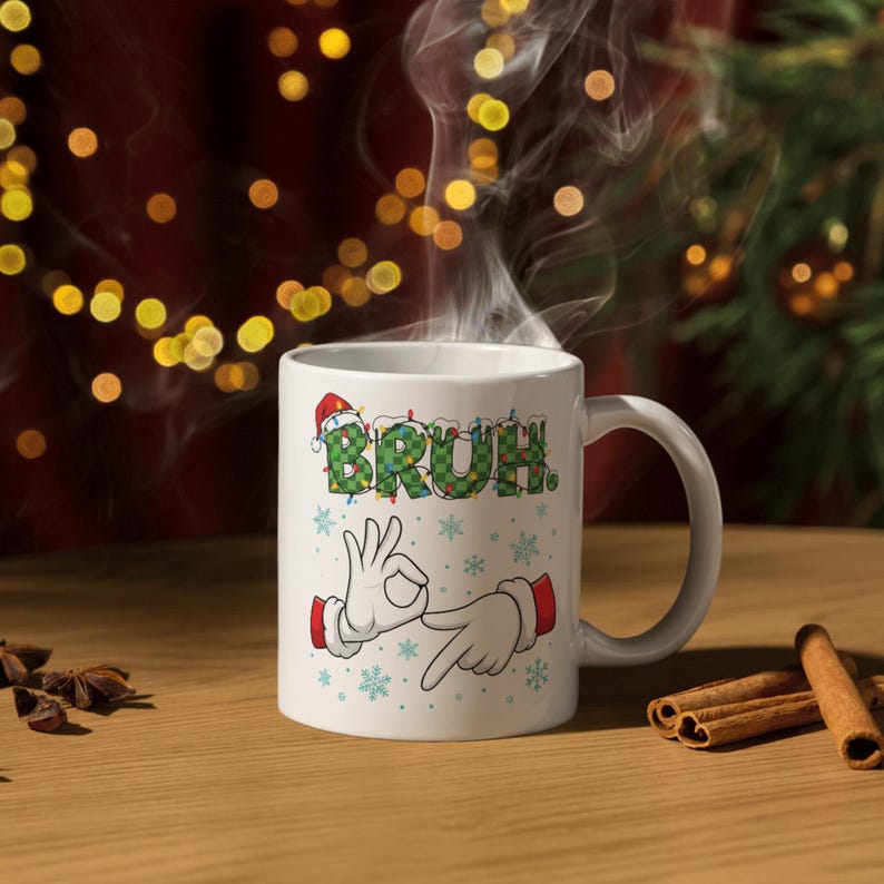May include: White ceramic mug with the word "BRUH" in green, Christmas-themed lettering, and a Santa hat. The mug features cartoon hands making an "okay" gesture. Steam rises from the mug, suggesting a hot beverage.