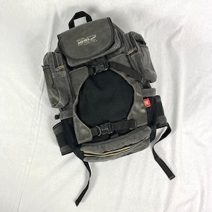 May include: A gray canvas backpack with black straps and a mesh pocket. The backpack has a brown leather patch with the text "DIESEL BORN" in white.