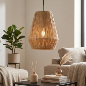 May include: A pendant light fixture with a woven, beige rope shade. The light has a tapered, bell-like shape and hangs from a black cord. The warm light from the bulb illuminates the textured surface. The fixture is a decorative element for home decor.