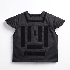 May include: A black sleeveless top featuring a round neckline and short, ribbed cap sleeves. The front is decorated with a geometric pattern of vertical and horizontal black rectangular fabric strips arranged in a symmetrical, block-like design.