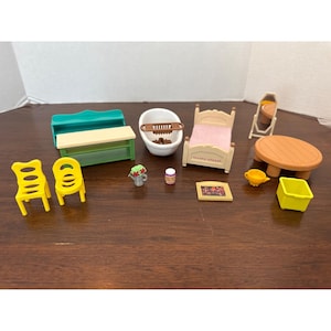 May include: A collection of miniature dollhouse furniture, including a bed with a pink blanket, a bathtub, a table, chairs, and a mirror. Other items include a small flower pot, a jar, a yellow watering can, and a yellow bin.