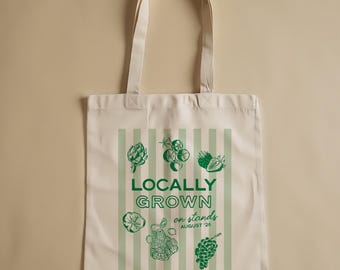Könnte beinhalten: Cremefarbene Tragetasche mit grünen vertikalen Streifen und Illustrationen von Obst und Gemüse. Der Text "LOCALLY GROWN on stands AUGUST '26" ist grün gedruckt. Die Tasche hat zwei cremefarbene Griffe.