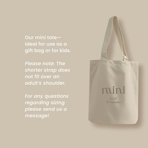 May include: A beige mini tote bag with a cream-colored handle. The bag has the word "mini" printed on it, along with the dimensions 9 x 12 inches and 15-inch handles. Text on the left side provides additional details.