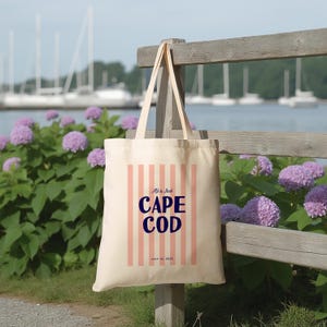 May include: A white canvas tote bag with pink and white stripes. The bag has the text "Ali & Jack Cape Cod July 22, 2023" printed on it.