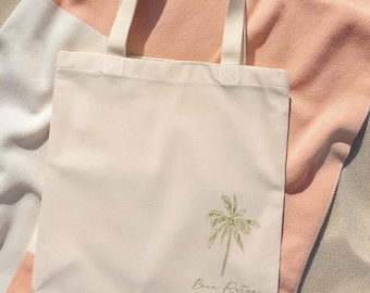Può includere: Una borsa tote in tela bianca con un design a palma verde e il testo "Boca Raton Jen & Frankie" stampato sul davanti.
