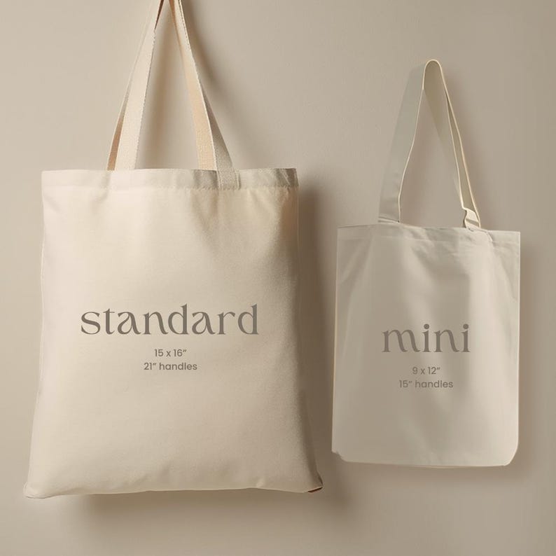 May include: Two off-white canvas tote bags. The larger bag is labeled "standard" and measures 15 x 16 inches with 21-inch handles. The smaller bag is labeled "mini" and measures 9 x 12 inches with 15-inch handles. Both bags have long handles.