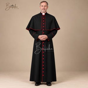 May include: A black cassock with a white clerical collar and red piping along the edges. The garment features a shoulder cape and a vertical row of red buttons down the front. The text Bespoke Thread is visible in the upper left and center.
