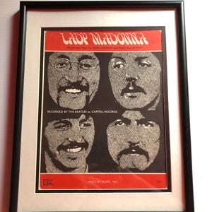 May include: A framed black and white photo of a sheet music cover for the song "Lady Madonna" by the Beatles. The cover features four black and white portraits of the band members. The text on the cover reads "Lady Madonna" and "Words and Music by John Lennon and Paul McCartney".