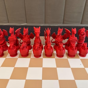 May include: A red dragon chess set with all the pieces on a brown and white chessboard. The pieces are all in their starting positions.