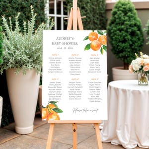 Puede incluir: Un cartel rectangular blanco de distribución de asientos para baby shower sobre un caballete de madera. El cartel presenta ilustraciones de naranjas en acuarela, el texto 'AUDREY'S BABY SHOWER JUNE 15, 2026', nombres por mesa y 'Please take a seat'.