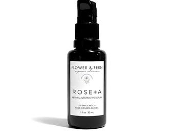 May include: A black glass pump bottle containing Rose+A Retinol Alternative Serum by Flower & Fern. The white label features the text: Flower & Fern organic skincare, Rose+A, Retinol Alternative Serum, 2% Bakuchiol + Rose-Infused Jojoba, 1 fl oz 30 mL.