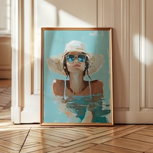 May include: A framed art print of a woman in a white hat and sunglasses, partially submerged in water. The artwork features a gold frame and a serene, summery color palette of blues, whites, and browns, evoking a sense of relaxation and leisure.