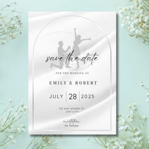 Könnte beinhalten: Eine weiße Save-the-Date-Karte mit einer grauen Silhouette eines Paares. Der Text lautet "save the date" mit dem Datum "July 28, 2025" und den Namen "Emily & Robert".