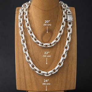 May include: A silver chain necklace displayed on a wooden bust. The necklace is shown in three lengths: 20 inches (50 cm), 22 inches (55 cm), and 24 inches (60 cm). The chain links are thick and oval-shaped, with a clasp closure.