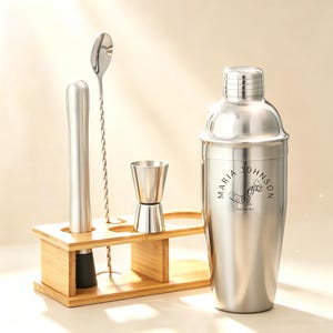 以下が含まれることがあります： 木製のホルダーが付いたステンレス製のカクテルシェーカーセット。セットには、「Maria Johnson」と印刷されたシェーカー、マドラー、バースプーン、ダブルジガーが含まれています。木製のホルダーには、各ツール用の切り欠きがあります。