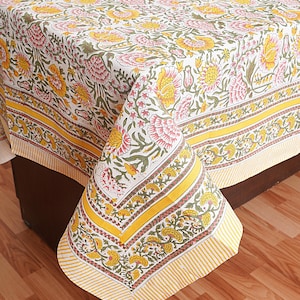 May include: A white tablecloth with a yellow and green floral print. The tablecloth has a yellow border with a white stripe.