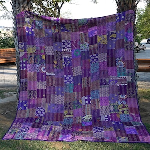 Peut inclure: Une courtepointe kantha violette fabriquée à partir de saris recyclés. La courtepointe est composée de nombreux carrés de tissu différents, chacun avec un motif unique. La courtepointe est un bel exemple de l'artisanat traditionnel indien.