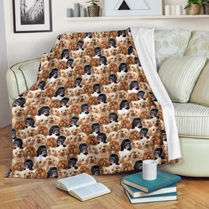 Könnte beinhalten: Eine gemusterte Decke mit einem sich wiederholenden Design von Cavapoo-Hundegesichtern in Braun-, Schwarz- und Cremetönen. Die Decke ist über ein Sofa drapiert, mit einer weißen Rückseite. Die Decke ist aus weichem Material.