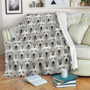 Puede incluir: Una manta blanca con un patrón repetido de caras de perros Labrador Retriever blancos. La manta está sobre un sofá, con un respaldo blanco visible. La manta está hecha de un material suave.