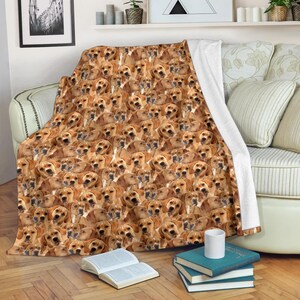 Può includere: Una calda coperta con un motivo ripetuto di cani marrone chiaro. La coperta è drappeggiata su un divano, con un retro bianco visibile. La coperta è realizzata in un materiale morbido ed è ideale per rilassarsi.