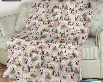 Könnte beinhalten: Eine Decke mit einem Muster aus weißen und hellbraunen Hunden, die über einem Sofa drapiert ist. Die Decke zeigt ein sich wiederholendes Muster von Hunden mit heraushängender Zunge. Die Decke ist über das Sofa gefaltet.