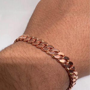 Puede incluir: Pulsera de cadena de eslabones de oro rosa. La pulsera presenta eslabones entrelazados, creando un accesorio audaz. El cálido tono metálico del oro rosa añade elegancia. Una pieza de declaración.
