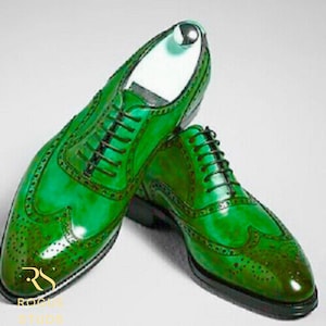 May include: A pair of green leather dress shoes with black laces. The shoes have a glossy finish and decorative perforations along the edges. The shoes are displayed on a white background.