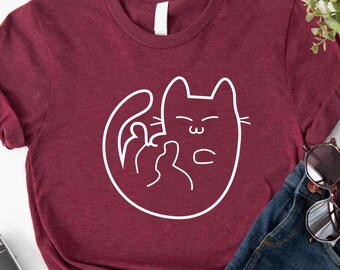 May include: A maroon t-shirt with a white outline of a cat giving the middle finger. The shirt is paired with denim shorts and sunglasses. The words "Custom Trendy Shirts" are in the lower left corner.