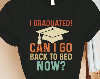May include: Black t-shirt with a vintage-style graphic that says "I Graduated! Can I go back to bed now?" with a graduation cap illustration.