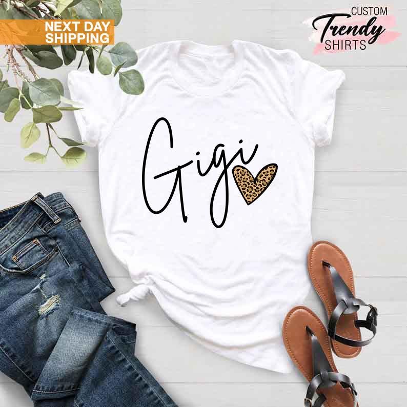 May include: White t-shirt with the word "Gigi" written in black cursive script and a leopard print heart.