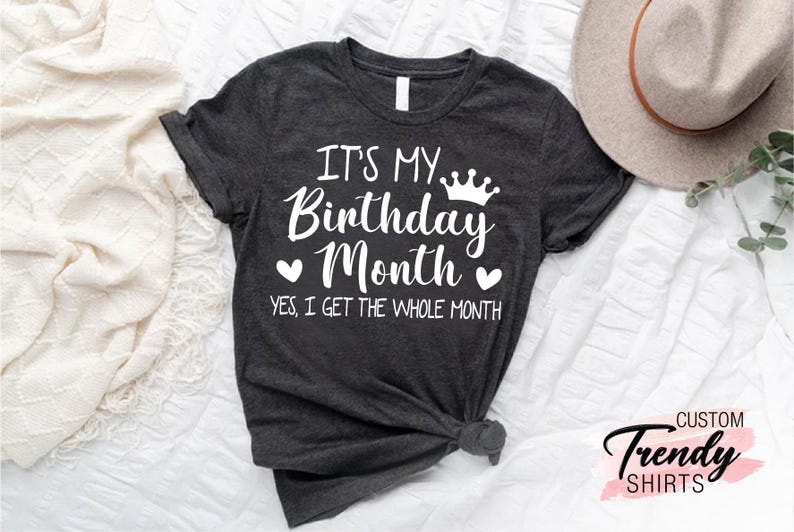 May include: A dark grey t-shirt with white text that reads "It's My Birthday Month" with a crown and hearts. The text below reads "Yes, I get the whole month."