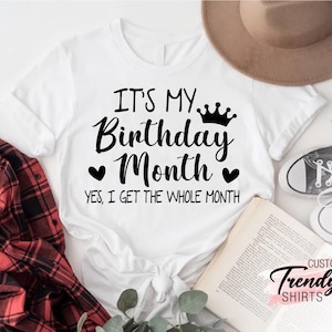 May include: White t-shirt with black text that reads "It's my Birthday Month. Yes, I get the whole month." with a crown and hearts above the text.