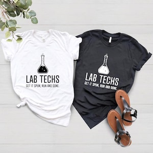 May include: Two t-shirts with a black and white graphic of a beaker and the text "Lab Techs Get it spun, run and done."