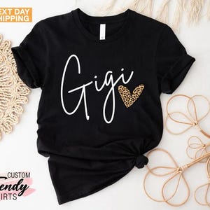 May include: Black t-shirt with the word "Gigi" written in white cursive script and a leopard print heart.